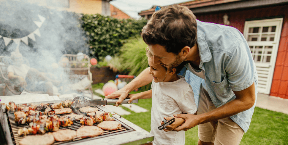Father and son grilling burgers and kabobs outside 